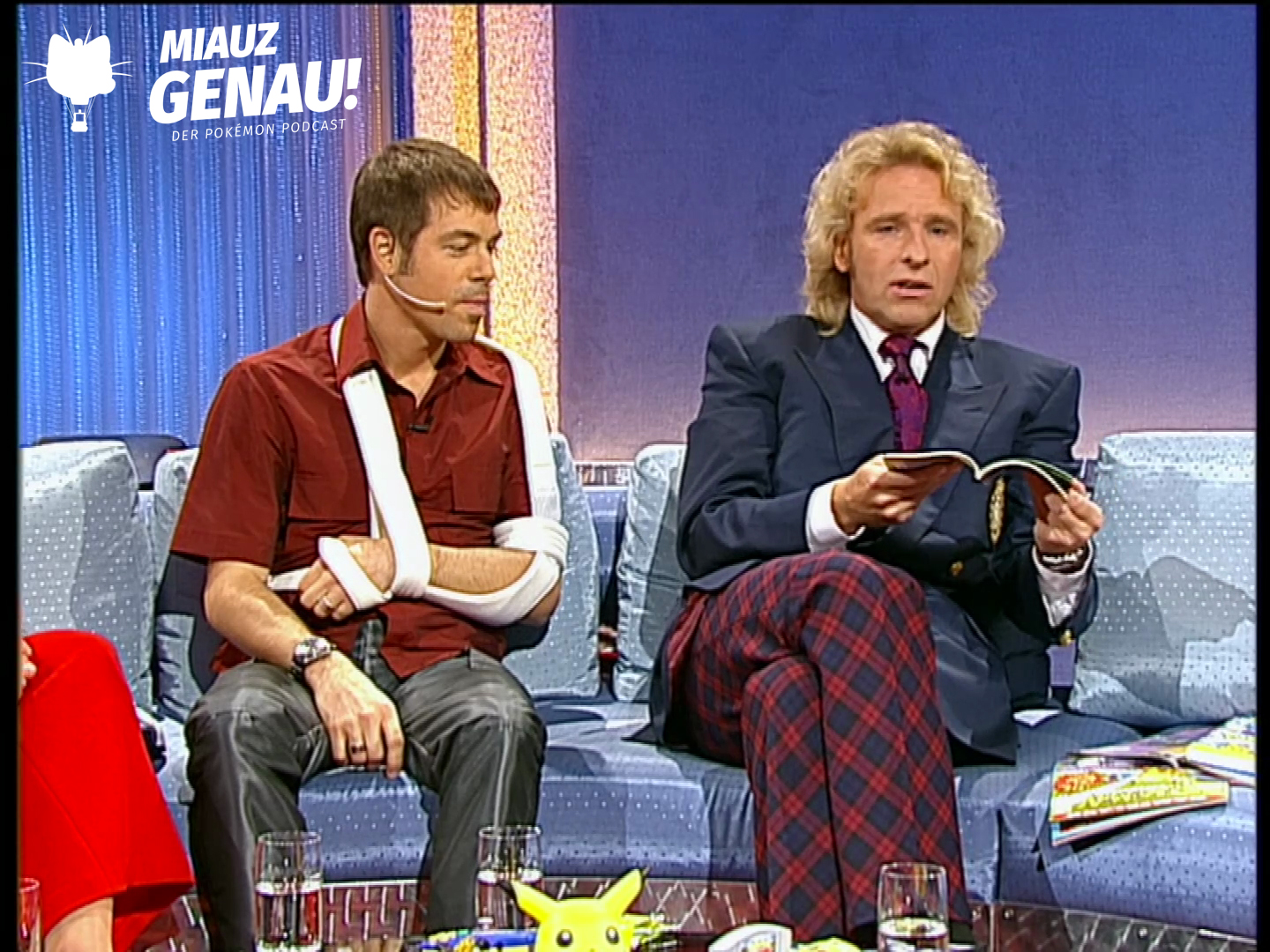 Thomas Gottschalk und Michael Mittermeier sitzen bei Wetten, dass..? auf dem Sofa, während Gottschalk in Pokémon-Material blättert.